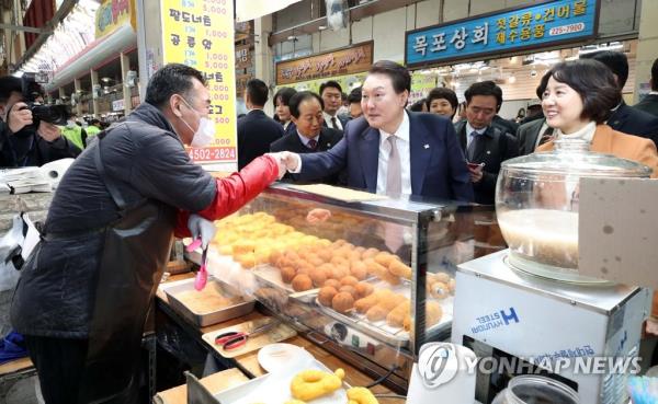 President Yoon Suk Yeol (2nd from R), accompanied by SMEs and Startups Minister Lee Young (R), shakes hands with a shopkeeper during a visit to a traditio<em></em>nal market in Cheongju, the capital of North Chungcheong Province, central South Korea, on Feb. 14, 2023. (Yonhap)