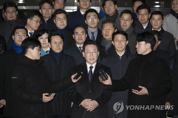The main opposition Democratic Party leader Lee Jae-myung (C) takes reporters' questions in front of the Seo<em></em>ngnam branch of the Suwon District Prosecutors Office in Seongnam, just south of Seoul, in this file photo taken Jan. 10, 2023, after being questio<em></em>ned by prosecutors over bribery allegations. (Pool photo) (Yonhap)