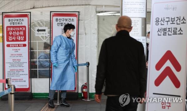 This file photo, taken Feb. 3, 2023, shows a medical worker in a blue gown and another man at a COVID-19 screening center in central Seoul. (Yonhap)