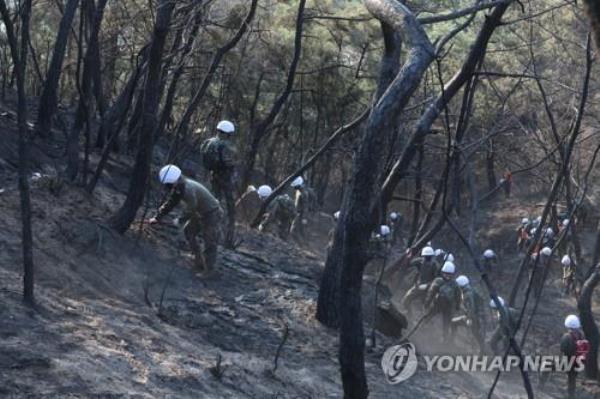 Firefighters and Army soldiers try to put out the smoldering fires on Mount Inwang in central Seoul on April 3, 2023. (Yonhap)