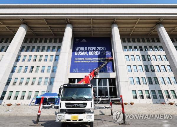 Work is under way to install a massive banner supporting South Korea's bid to host the 2030 World Expo in the southeastern port city of Busan at the Natio<em></em>nal Assembly in Seoul on April 2, 2023. (Yonhap)