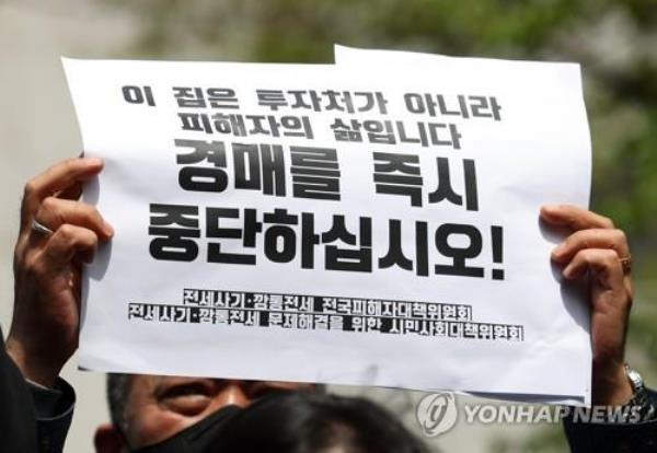 A man holds up a protest message outside the Incheon District Court in Incheon, 27 kilometers west of Seoul, on April 21, 2023, calling for remedies for victims of home rental scams. (Yonhap)