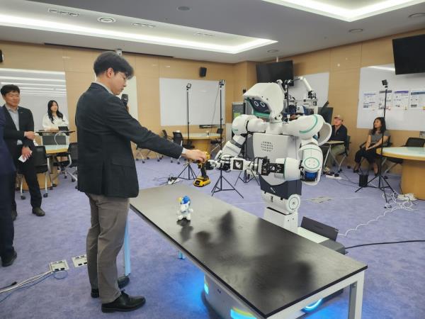 Professor Bae Joon-bum (L) hands a drill to a robot named Avatar at a lab of the Ulsan Natio<em></em>nal Institute of Science and Technology on April 28, 2023. (Yonhap)