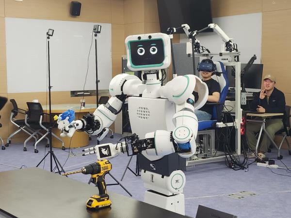 Avatar (L), a robot developed by professor Bae Joon-bum and his team, and its operator (2nd from R) pose for the camera at a lab of the Ulsan Natio<em></em>nal Institute of Science and Technology on April 28, 2023. (Yonhap)
