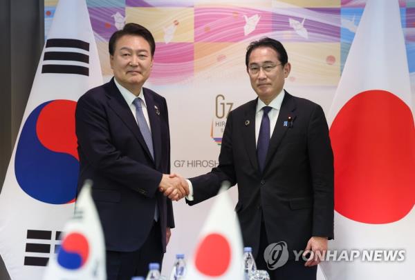 South Korean President Yoon Suk Yeol (L) and Japanese Prime Minister Fumio Kishida shake hands during a summit in Hiroshima, Japan, in this May 21, 2023, file photo. (Yonhap)