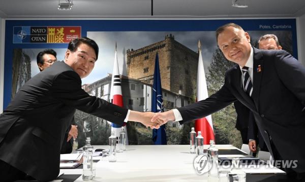 South Korean President Yoon Suk Yeol (L) shakes hands with Polish President Andrzej Duda as they meet on the sidelines of a summit of the North Atlantic Treaty Organization at the IFEMA Co<em></em>nvention Center in Madrid, in this file photo taken June 29, 2022. (Yonhap)