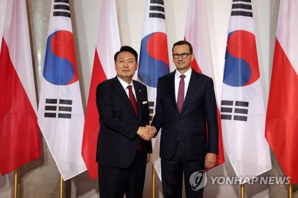 South Korean President Yoon Suk Yeol (L) and Polish Prime Minister Mateusz Morawiecki shake hands during a meeting at the prime minister's office in Warsaw on July 13, 2023. (Pool photo) (Yonhap)