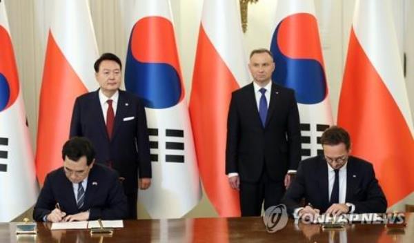 This photo shows South Korean Industry Minister Lee Chang-yang (L) and Polish Minister of Eco<em></em>nomic Development and Technology Waldemar Buda (R) signing a memorandum of understanding on establishing a Trade and Investment Promotion f<em></em>ramework between the two countries at the presidential palace in Warsaw on July 13, 2023, as South Korean President Yoon Suk Yeol (L, back row) and Polish President Andrzej Duda watch. (Yonhap)