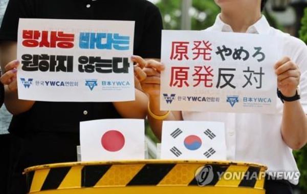 Members of South Korea's YWCA and Japan's YWCA hold up signs reading, 