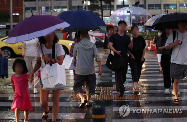 People walk on a crosswalk near Seoul Station in the capital on July 30, 2023. (Yonhap)