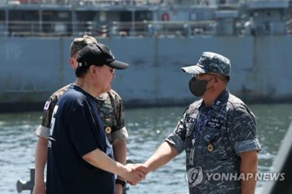 President Yoon Suk Yeol (L) shakes hands with a naval officer during a visit to a naval ba<em></em>se in Jinhae, 311 kilometers southeast of Seoul, on Aug. 3, 2023, taking time out of his weeklong summer vacation, in this photo provided by the presidential office. (PHOTO NOT FOR SALE) (Yonhap)