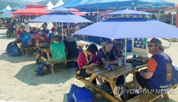 Participants in the 25th World Scout Jamboree rest under large parasols installed at the Saemangeum campground in southwestern South Korea on Aug. 7, 2023, to avoid scorching heat. (Yonhap)