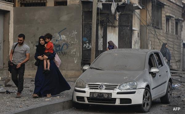 Residents walk along a debris-strewn street following Israeli air strikes in Gaza on Sunday