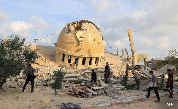 A man and children walk on the ruins of a mosque destroyed in Israeli airstrikes in Khan Yunis, southern Gaza Strip