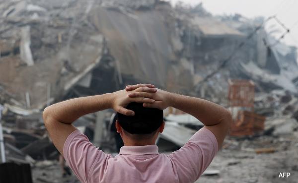 Residents walk around a building that collapse during an Israeli air strike in Gaza City on Sunday 