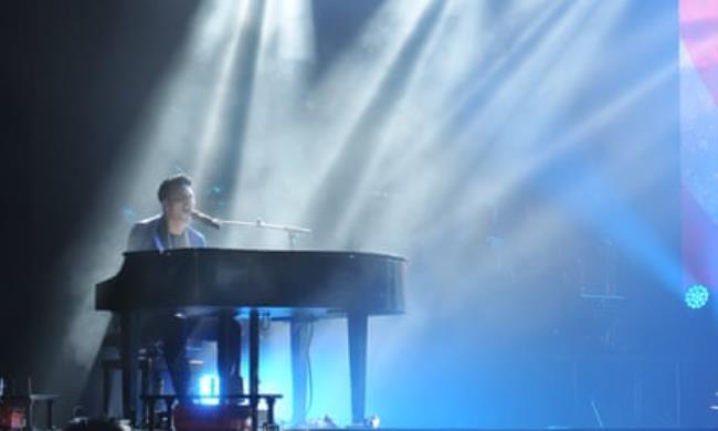 Spotlit singer performs at the piano