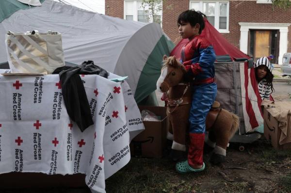 Venezuelan migrants play outside their tents as they join dozens of migrants trying to keep warm with do<em></em>nated jackets, blankets and tents on Leland Avenue outside the 17th District Chicago police station, Oct. 10, 2023. 